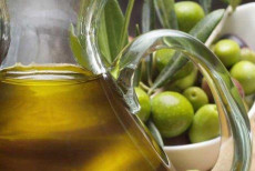 Una brocca d'olio accanto a un grappolo di olive.