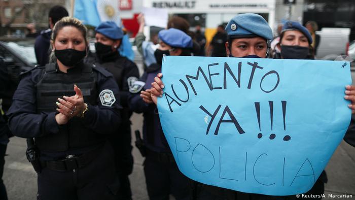 Agenti della polizia portano un cartello con la scritta "Aumento giá" durante una protesta in Buenos Aires.