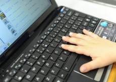 La mano di un bambino su una tastiera di un computer collegato a internet.