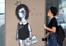 Una donna all'ingresso di un aula di scuola a Tel Aviv. Sulla porta il disegno di una bimba con il cartello : "No agli abbracci"
