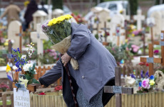 Una persona depone fiori su una tomba al cimitero Laurentino a Roma in occasione della ricorrenza di Ognissanti.