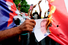Un manifestante brucia un'immagine di Macron durante una protesta islamica contro la Francia, a Bangladesh