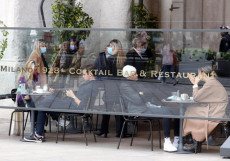 Alcune persone in un bar in piazza del Duomo a Milano durante la pausa pranzo.