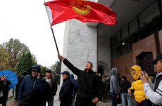 Una manifestante sventola una bandiera del Kirghizistan durante proteste contro il risultato delle elezioni párlamentari in Bishkek
