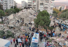 Soccorritori e volontari cercano corpi fra loe macerie di un palazzo a Smirne.