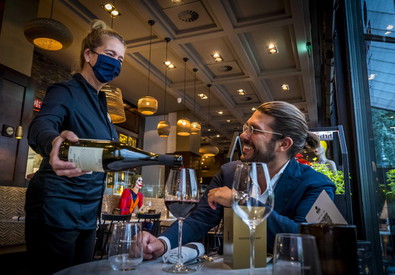 Un cameriere versa del vino nel bicchiere di un cliente ad un ristorante in Amstertdam