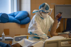 Un un infermiere sostiene la mano di un paziente di Covid-19 in una unitá di terapia intensiva in un ospedale di Praga.