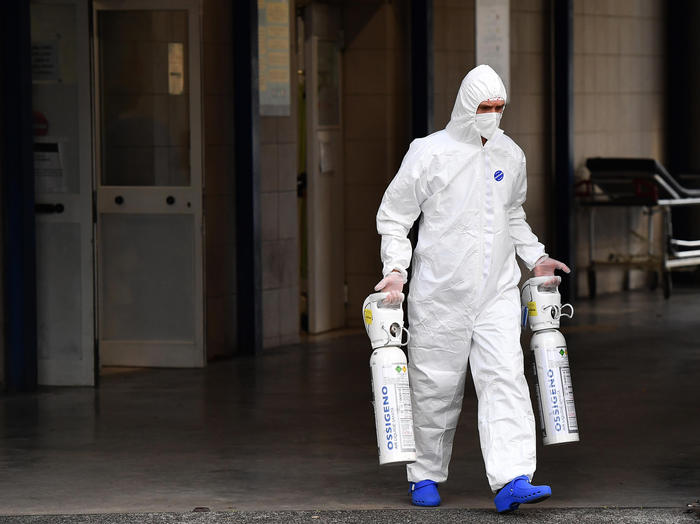 Un operatore sanitario dell'ospedale San Filippo Neri a Roma con due bombole d'ossigeno