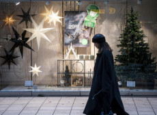 Una donna passeggia davanti ad un negozio decorato per le feste di Natale