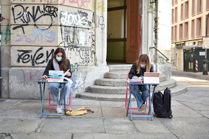 Lisa e Anita, due studentesse della scuola media Italo Calvino di via Sant'Ottavio, sedute al banco in strada, fuori dalla scuola.