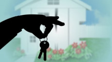 Una mano tende in mazzo di chiavi, sullo sfondo di una palazzina in un' Immagine allegorica allo sfratto.