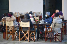 Un gruppo di persone ai tavolini di un bar, a Genova,