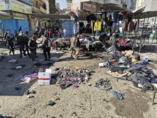Cittadini camminano nel mercato della piazza Tayyaran di Bagdad dopo l'attentato suicida.