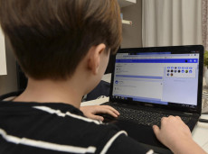 Un bambino chattando con un computer portatile.