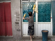 Una donna cinese pulisce una finestra. (Ansalatina)