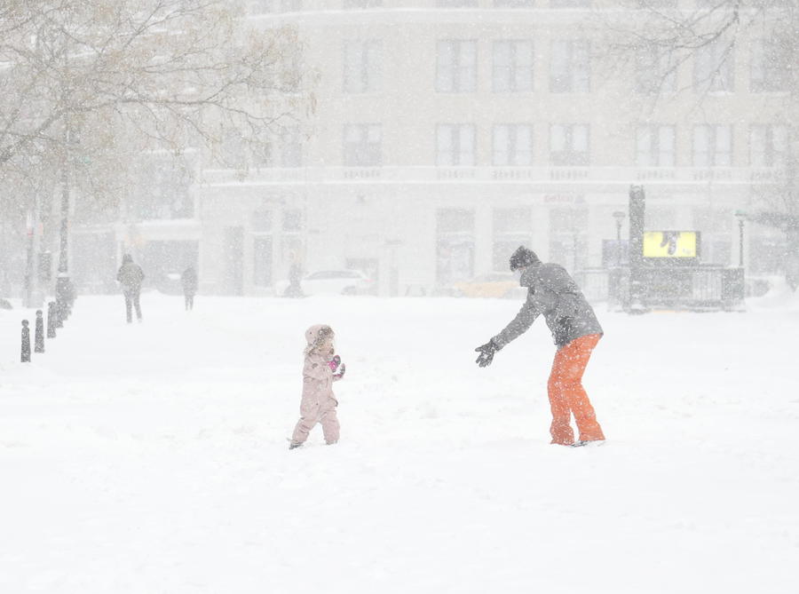 Padre e figlio giocano con la neve durante una bufera a Union Square in New York.