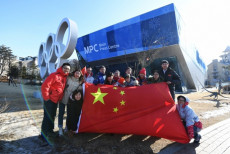 Personale del Comitato Organizzatore e volontari dei Giochi Invernali mostrano la bandiera cinese davanti al Centro Stampa