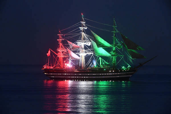 Un'immagine della nave-scuola Amerigo Vespucci illuminata con i colori della bandiera italiana alla fonda nel porto di Genova.
