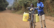 Un bambino trasporta acqua in bicicletta in un villaggio africano.