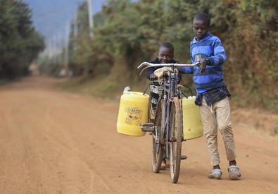 Un bambino trasporta acqua in bicicletta in un villaggio africano.