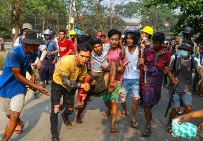 Manifestanti caricano in braccia un ferito durante le proteste in Birmania