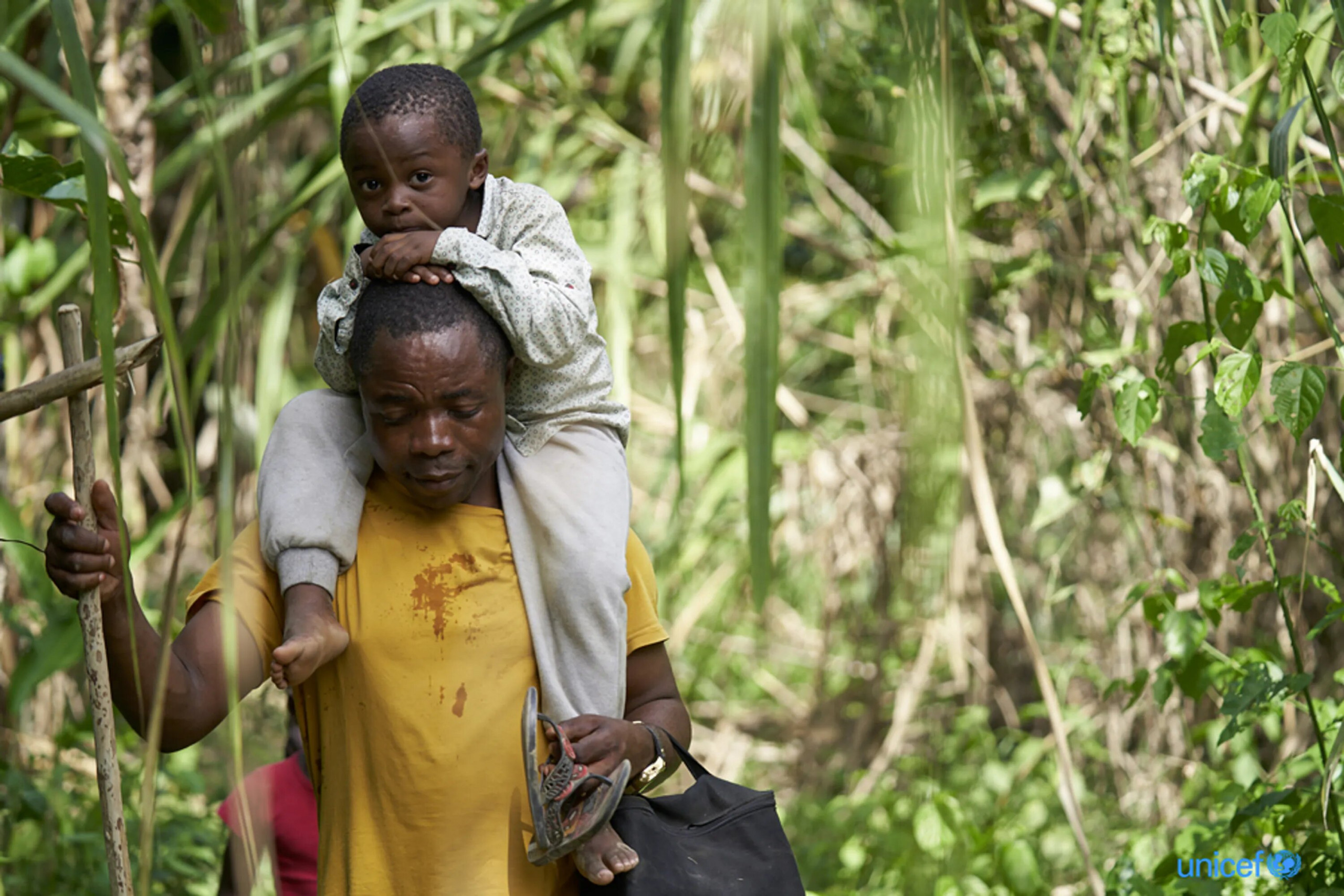 Un migrante con un bambino sulla spalla attraversa la giungla al confine della Colombia con Panamá.