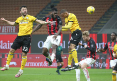 Kessie colpisce di testa il pallone tra due difensori dell'Udinese.