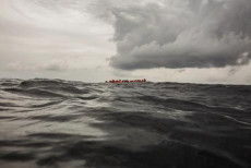 Migranti in un barcone in mezzo al mare.
