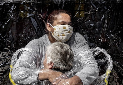 La foto vincitrice del premio World Press Phoho 2021: Una infermiere abbraccia una anziana coperta da un plastico trasparente.