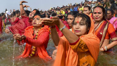 Devote innalzano l'acqua sagrata in preghiera durante la cerimonia del Kumbha Mela in India.