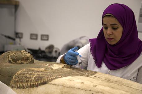 Un'archeologa egizziana lavora su una mummia al Grande Museo Egiziano di Giza, Egitto.