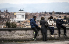 Persone sedute su un muretto dal Pincio su Roma.