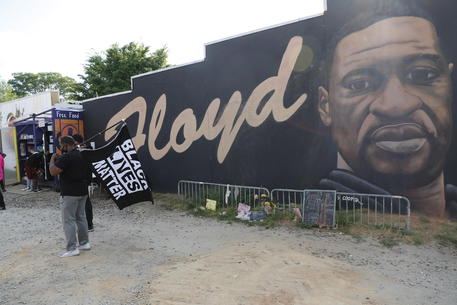 Una manifestazione passa davanti un murale di George Floyd in Minneapolis, Minnesota.