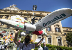 Un manifestante porta un aereo di cartone surante una protesta dei lavoratori di Alitalia