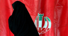 Una suora passa davanti una bandiera dell'Iran.