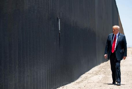 L'ex presidente degli Usa Donald Trump cammina a fianco al muro del confine con il Messico.