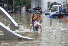 Un uomo porta a cavalluccio a una donna in mezzo a una strada annegata nella cittá di Zhengzhou, provincia di Henan. Cina