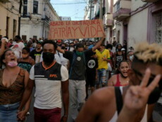 Manifestanti portano uno striscione con la scritta "abasso la dittatura, patria e vita" durante una protesta all'Havana.