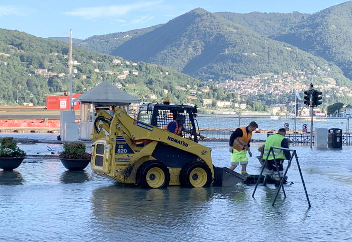 Operai al lavoro in piazza Cavour a Como ricoperta di acqua e detriti esondati dal lago a causa delle copiose piogge dell'altra sera. Como