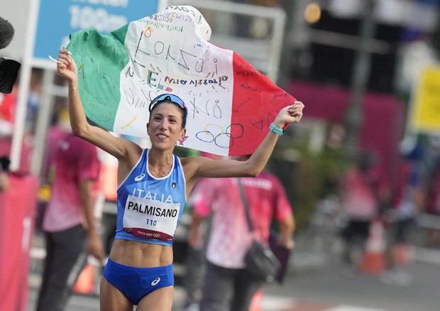Antonella Palmisano festeggia con la bandiera italiana sulle spalle.