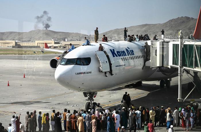 Afghani cercano di imbarcare su un aereo per fuggire dal paese.