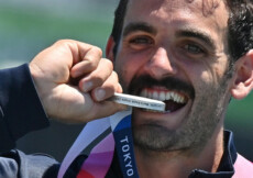 Manfredi Rizza, sorridente, morde la medaglia d'argento.
