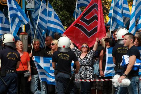 Seguitori di Alba Dorata scentolano le bandiere con la "greca", segno simile alla svastica.