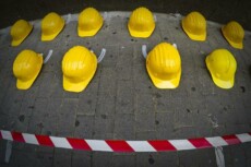 Manifestazione contro gli incidenti sul lavoro, caschi gialli a terra.