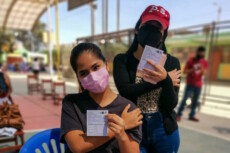 Ragazze peruviane mostrano il loro certificato di vaccinazione.