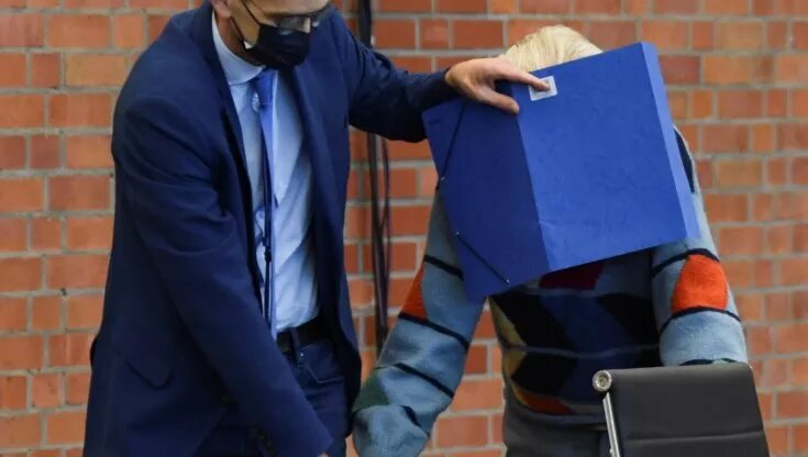 L'ex SS Josef Schuetz entra nel tribunale con il volto cooperto da una cartella blu per proteggersi dalle telecamere dei giornalisti: