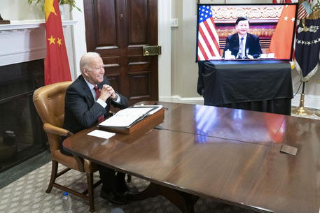 Il presidente Joe Biden seduto nella Roosvelt room della Casa Bianca parla con il presidente cinese Xi Jinping visibile nello schermo