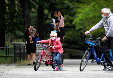 Una bambina in bici nel parco con il padre.