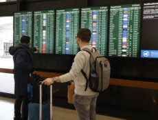 Due passeggeri controllano i ritadi dei voli sul tabellone nell'aeroporto di San Francisco.