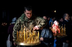 Un soldato ucraino accende una candela nella cattedrale di Kie